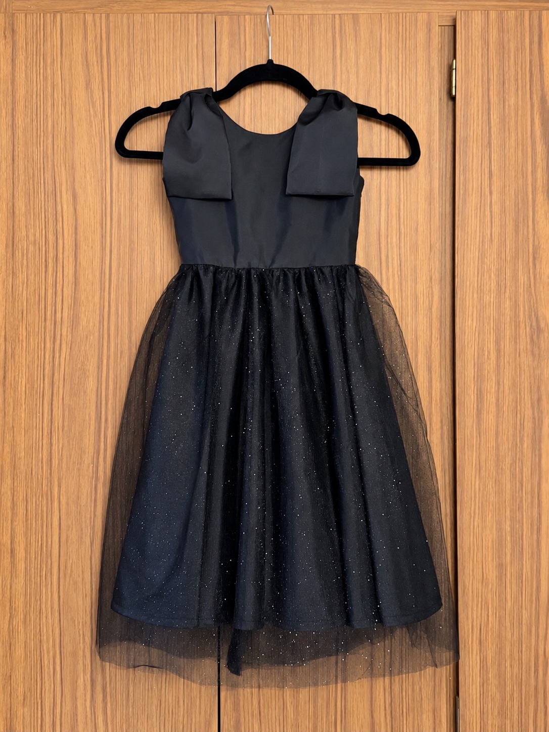 Handmade black party dress with bow shoulders and a sparkle tulle skirt, on a hanger